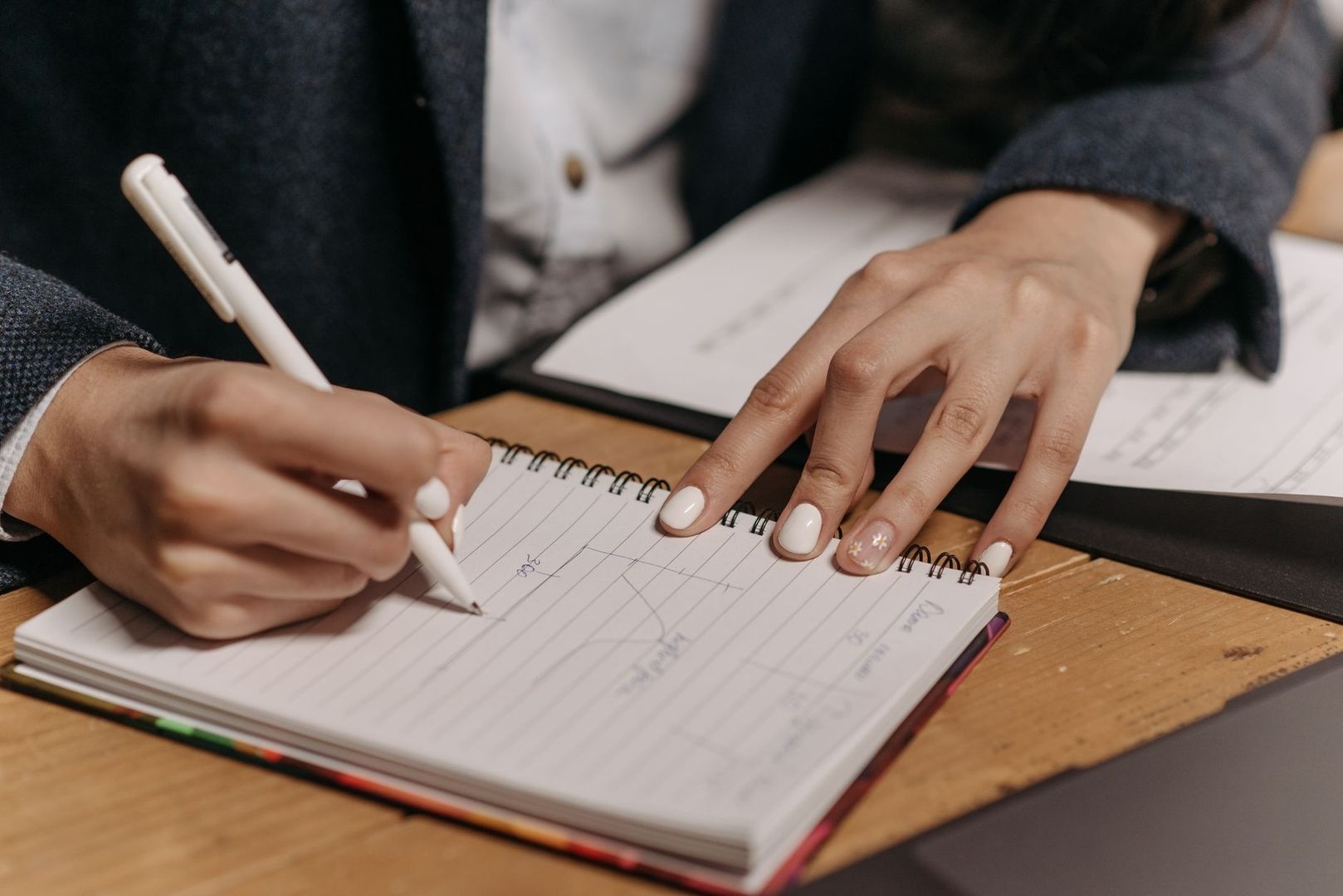 Persoon maakt handgeschreven notities in een spiraalnotitieboek